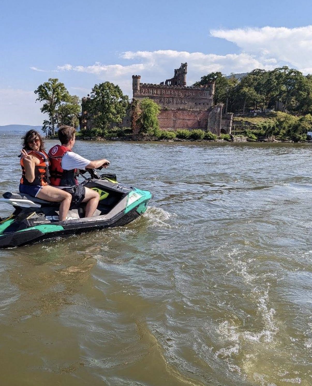 Two riders on a jet ski in front of Bannerman's Island Arsenal on the Hudson River